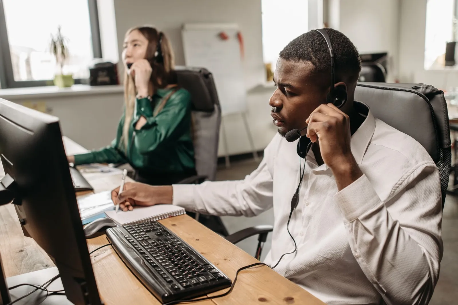 Customer service agents with headsets working from CRM records on their computers