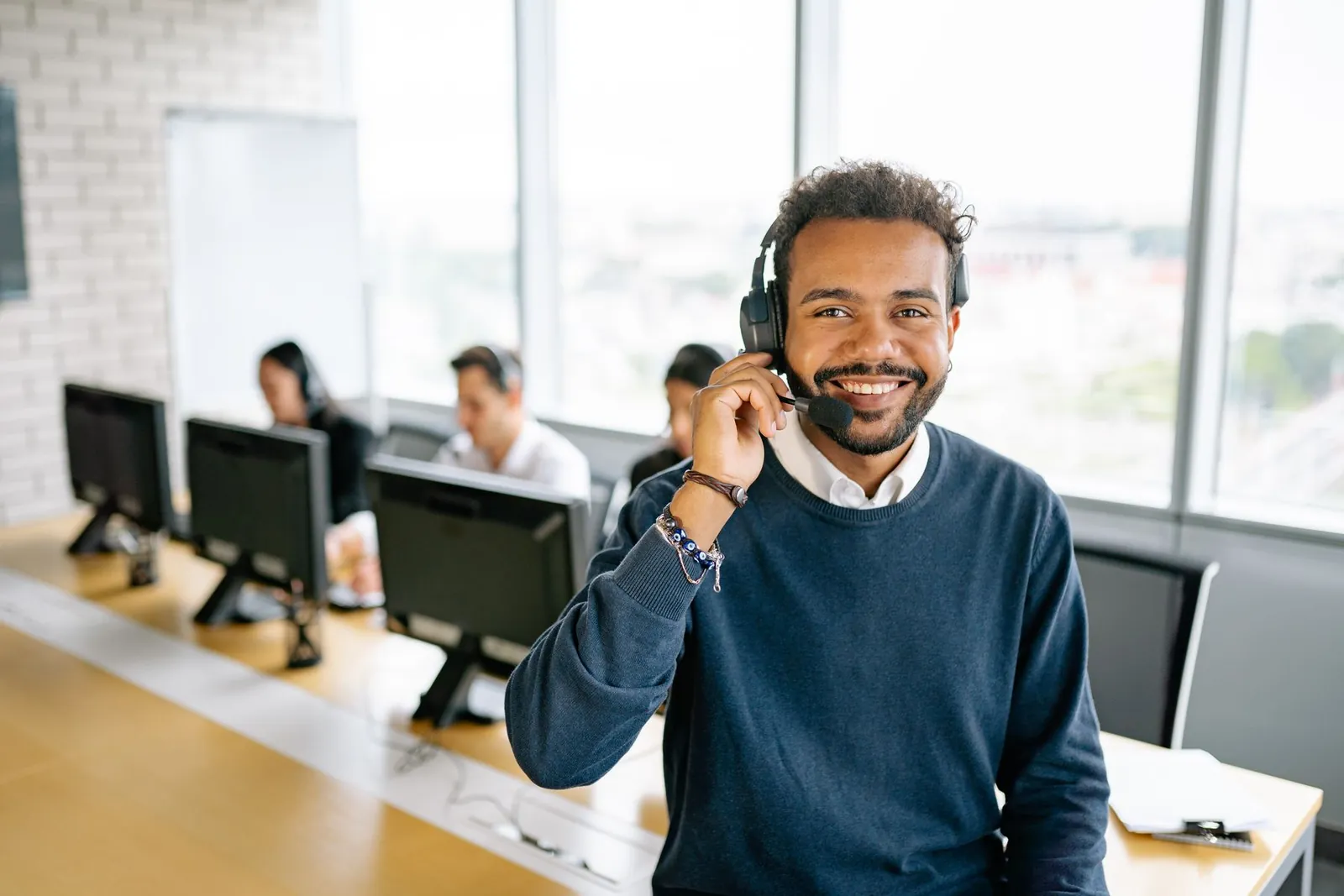 Smiling outbound sales agent wearing a headset in a modern contact centre