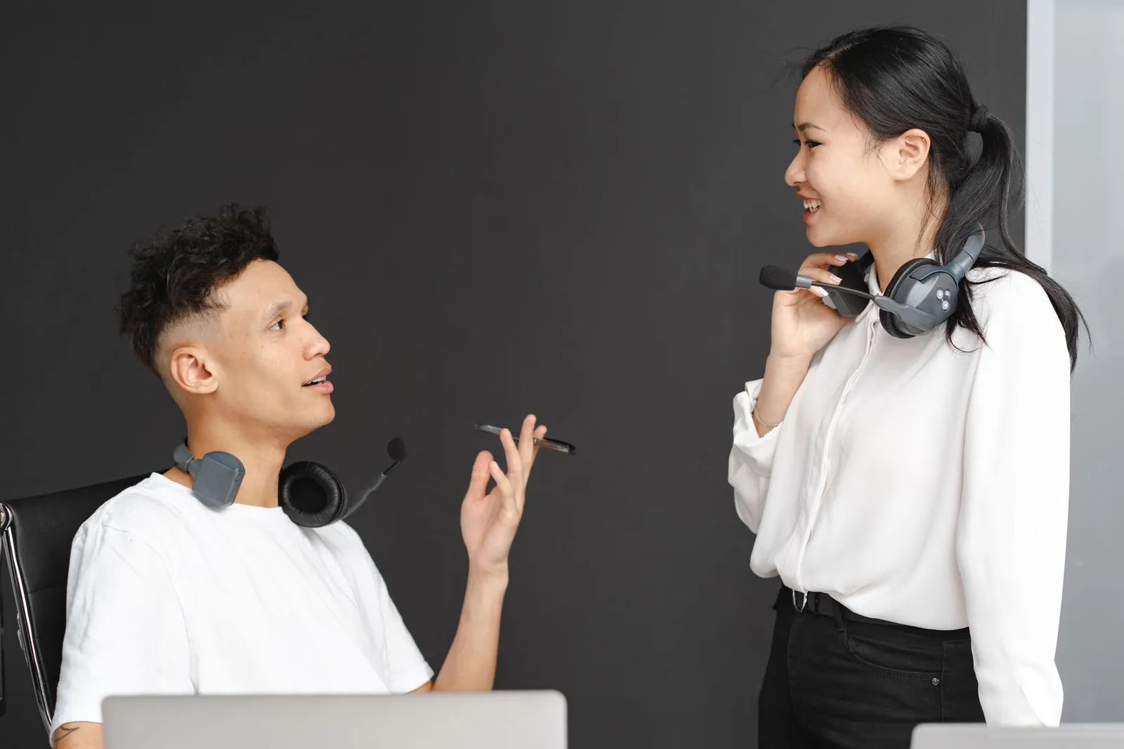 Two contact centre colleagues with headsets talking in a modern office